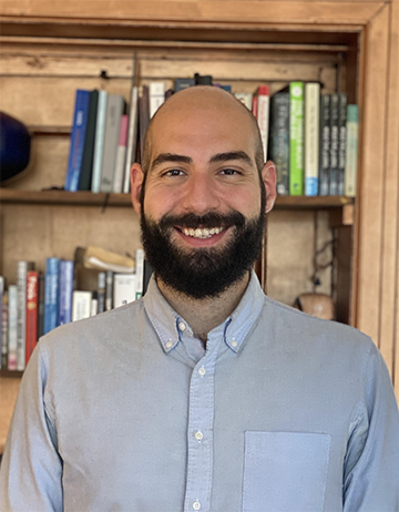 Dr. Berk Birand standing in front of a book shelf